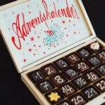 Caixa de chocolates decorados com cobertura representando números de um a 30, de coloração branca