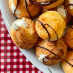 croquembouche com calda de chocolate sobre uma mesa forrada com pano xadrez vermelho e branco