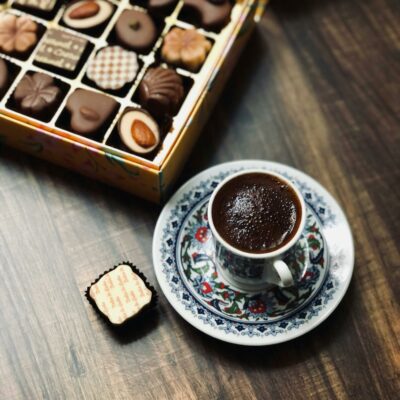 Caixa de chocolates dispostos à mesa junto a uma xícara de café